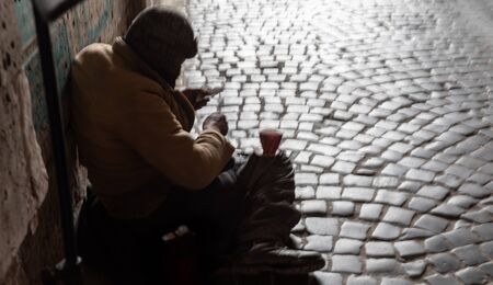 Homeless man. Blurred image of a beggar sitting on the street and waiting for alms.