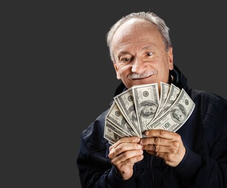 Senior gentleman holding a stack of money. Portrait of an excited old man. Happy old man holding...