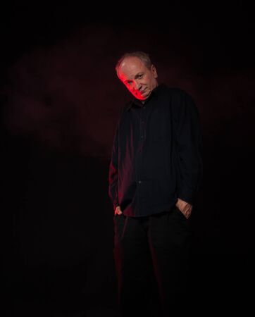 Old macho man. Portrait of an elderly emotional man on a dark background in the studioの写真素材