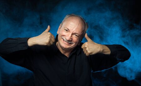 Old macho man. Happy elderly man gesturing showing thumb up. Portrait of an elderly emotional man on...