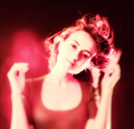 Portrait of a beautiful young woman with hair flying. Abstract soft focus romantic portrait of a young woman in light pink tonesの写真素材