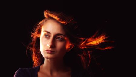 Studio romantic portrait of a young woman on dark background