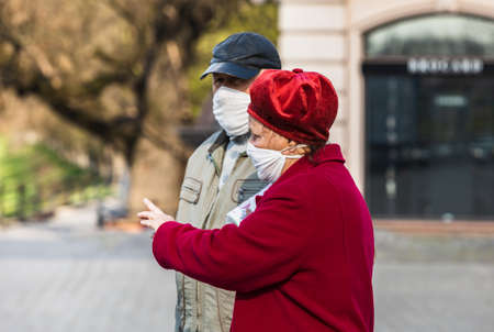 Uzhgorod, Ukraine - Apr. 10, 2020: People in medical masks on the street rush about their business during the coronavirus epidemic. Elderly happy coupleのeditorial素材