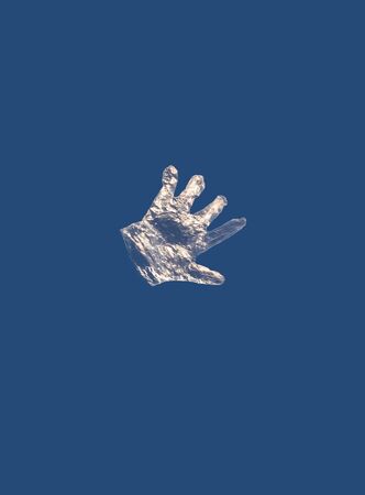 A disposable plastic glove flies against a blue sky during a coronavirus epidemicの写真素材