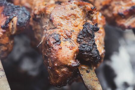 Meat on skewers. Marinated shashlik preparing on a barbecue grill over charcoal. Appetizing meat grilled on skewers. Cooking shashlik. Grilling pork on coalの写真素材