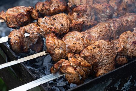 Meat on skewers. Marinated shashlik preparing on a barbecue grill over charcoal. Appetizing meat...