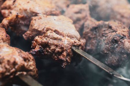 Meat on skewers. Marinated shashlik preparing on a barbecue grill over charcoal. Appetizing meat grilled on skewers. Cooking shashlik. Grilling pork on coalの写真素材