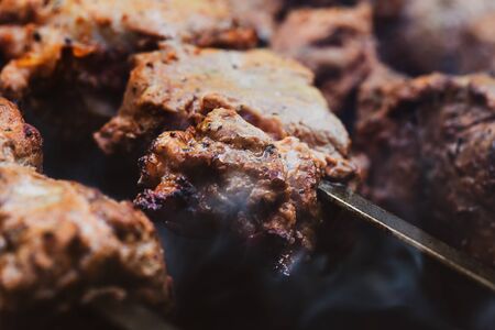Meat on skewers. Marinated shashlik preparing on a barbecue grill over charcoal. Appetizing meat grilled on skewers. Cooking shashlik. Grilling pork on coalの写真素材