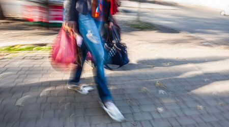 Young woman with bags and packages on the road in the city. Intentional motion blurの写真素材