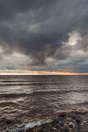Amazing dramatic landscape. Dramatic dark clouds during sunset at sea. Dark sea water and heavy...