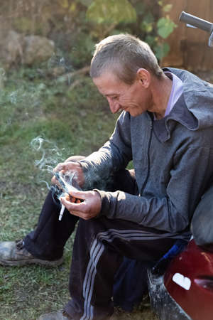 LUG, UKRAINE - Nov. 07, 2020: Young rural worker guy resting while sitting near his motorcycle...