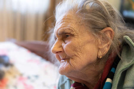Old woman. Portrait of very old tired woman in depression sitting indoors on bedの写真素材