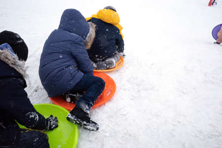 KYIV, UKRAINE - Jan. 30, 2021: Outdoor winter fun. Children sledding and snowboarding in a big city after a snowfall. Active winter outdoors games. Everything is covered with snow aroundのeditorial素材