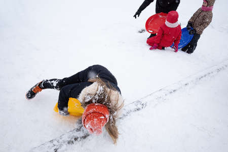 KYIV, UKRAINE - Jan. 30, 2021: Outdoor winter fun. Children sledding and snowboarding in a big city after a snowfall. Active winter outdoors games. Everything is covered with snow aroundのeditorial素材