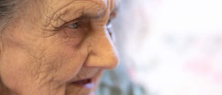 Old woman. Portrait of very old tired woman in depression sitting indoors on bedの写真素材