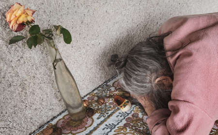 Old woman. An elderly woman near her house in a village put her head on the table to save herself from headaches and depressionの写真素材