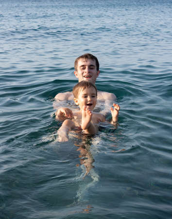 Happy family and healthy lifestyle. A young father teaches a child to swim in the seaの写真素材