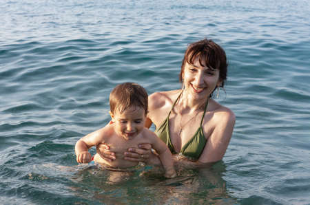 Happy family and healthy lifestyle. Young mom teaches a child to swim in the seaの写真素材