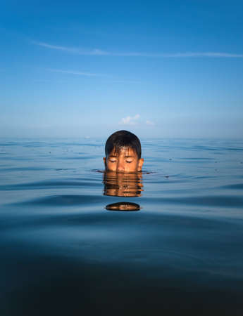 Relaxation and healthy lifestyle. Young boy teenager bathes in the sea.の写真素材