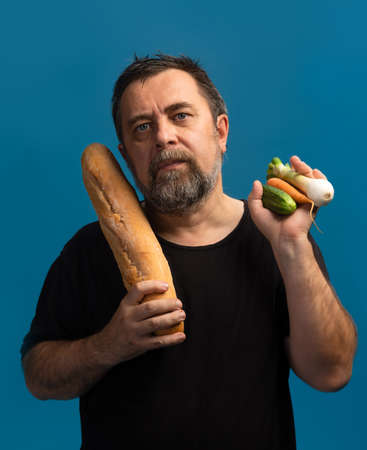 Healthy lifestyle concept. Hard choise. What is better bread or vegetables. A middle-aged man in a...