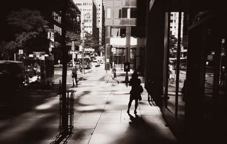 NEW YORK, USA - Sep 23, 2017: Manhattan street scene. Light and shadows on Lexington Ave. Silhouette of a lonely young woman in sun light reflected from skyscrapers. Sepia toned image in vintage styleのeditorial素材