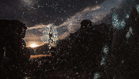 Reflection of the sunset sky in the broken glass of the car. Car glass shattered by a stone. Broken...