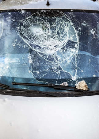 Car glass shattered by a stone. Broken car windshield. Criminal incidents. Vandals, hooligans mutilated the car, smashed the windshieldの写真素材