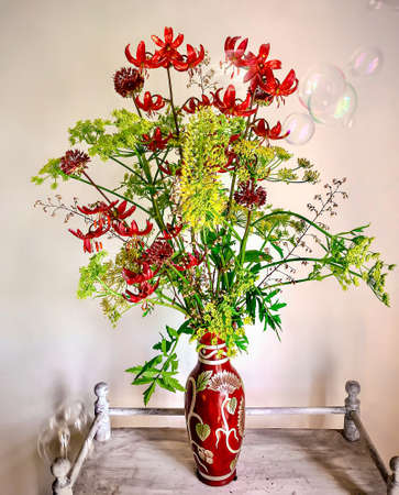 Art of arranging bouquets of flowers. Romantic bouquet on a coffee table with soap bubbles. In composition lily martogon, allium, parsnip, geykhera, eremurusの写真素材
