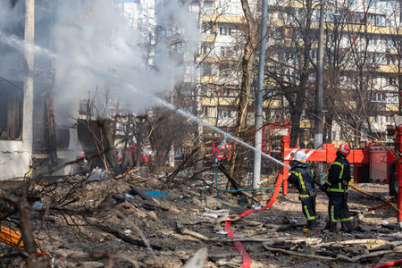 KYIV, UKRAINE - Mar. 15, 2022: War in Ukraine. Firefighters fighting a fire in a residential building that was hit by a Russian shell.のeditorial素材