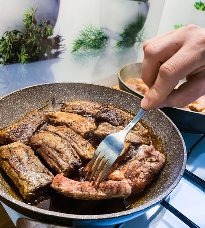 Fried Pork Ribs in big frying pan on gas stove in home kitchenの写真素材