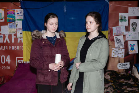 KYIV, UKRAINE - Mar. 25, 2022: War in Ukraine. Subway station serves as a shelter for thousands of people during a rocket and bomb attack. Two girls near the exhibition of children's anti-war drawingsのeditorial素材