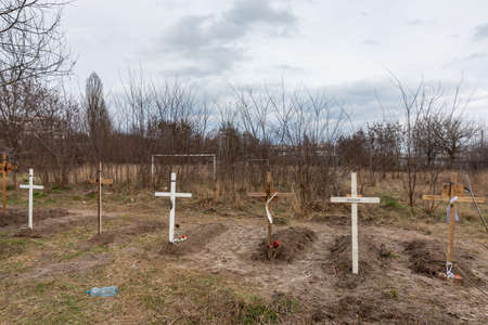 BUCHA, UKRAINE - Apr. 06, 2022: Graves with bodies of civilians next to apartments blocks in the...