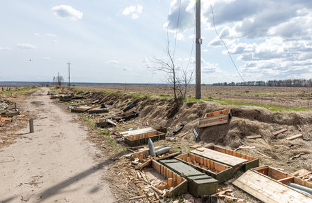 ANDRIIVKA, UKRAINE - Apr. 12, 2022: Abandoned equipment, shells and empty boxes of weapons are lying in the middle of the field along the road near Andriivka after the retreat of Russian troops.のeditorial素材