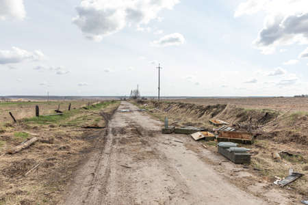 ANDRIIVKA, UKRAINE - Apr. 12, 2022: Abandoned equipment, shells and empty boxes of weapons are lying in the middle of the field along the road near Andriivka after the retreat of Russian troops.のeditorial素材