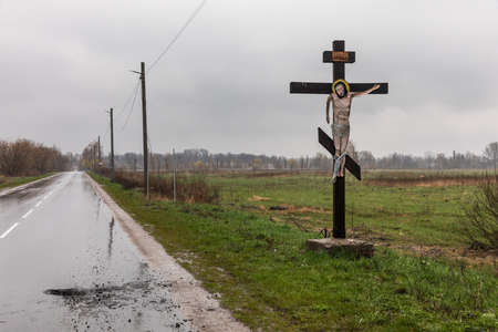Blystavycia village, Kyiv region, Ukraine, Apr. 22, 2022: Crucifixion of Christ with lowered hand near the road with traces of rocket and mine explosionsのeditorial素材