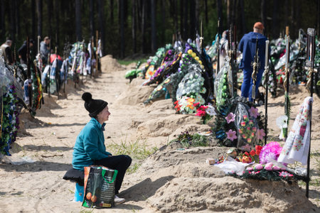 IRPIN, UKRAINE - May. 01, 2022: A large number of fresh graves in the cemetery in Irpin. People commemorate their loved ones at the cemeteryのeditorial素材