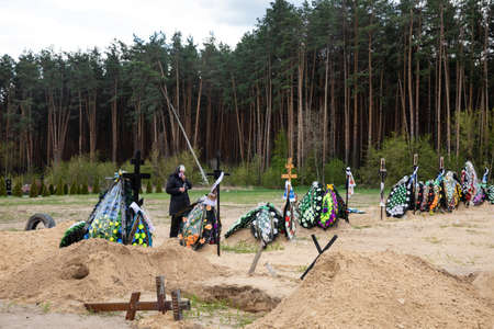 IRPIN, UKRAINE - May. 01, 2022: A large number of fresh graves in the cemetery in Irpin. People...