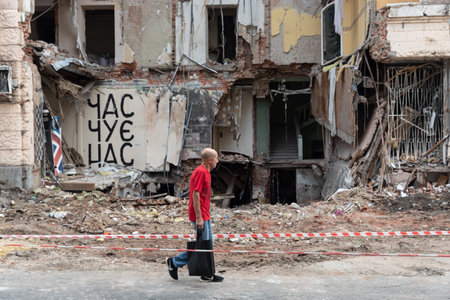 KHARKIV, UKRAINE - Jul. 28, 2022: A local male is seen walking past a destroyed house. The...