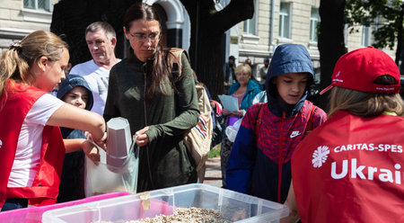 KHARKIV, UKRAINE - Aug. 02, 2022: A volunteer girl pours oatmeal into plastic bags for people in the grocery line. Volunteer organization Caritas Ukraine distributes food to the needy in Kharkivのeditorial素材