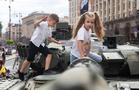 KYIV, UKRAINE - Aug. 20, 2022: Children on tanks. An exhibition of destroyed Russian equipment is...