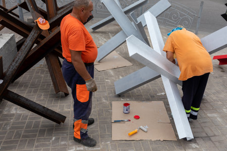 KYIV, UKRAINE - Aug. 20, 2022: Workers paint anti-tank hedgehogs. Exhibition of destroyed Russian military equipment on Khreshchatyk in Kyiv in honor of Ukraine's Independence Day.のeditorial素材