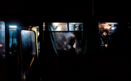 KYIV, UKRAINE - Dec. 16, 2022: Passengers of a bus are seen behind misted windows during a blackout in Kyiv at night.のeditorial素材