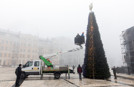 KYIV, UKRAINE - Dec. 17, 2022: Public utilities workers set up and decorate a Christmas tree on Sofiyivska Square in Kyiv on a foggy dayのeditorial素材