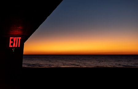 The inscription Exit on the building on the seashore during sunset. Focus on lettering. Soft blur image of sunset at seaの写真素材