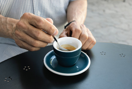 Lifestyle concept. An elderly man drinking espresso coffee at an outdoor cafe in the early hours of...