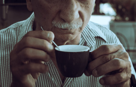 Lifestyle concept. An elderly man drinking espresso coffee at an outdoor cafe in the early hours of the morning before work.の写真素材
