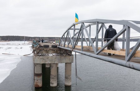 KHARKIV REG., UKRAINE - Mar. 02, 2023: Temporarily restored pedestrian crossing over destroyed bridge across Siverskyi Donets River in Staryi Saltiv, Kharkiv regionのeditorial素材