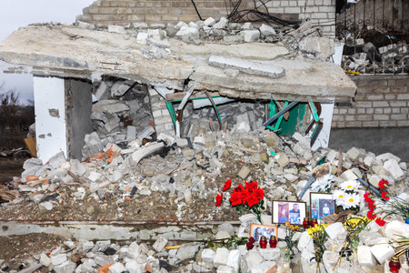 IZYUM, UKRAINE - MAR. 19, 2023: Photos of the dead, commemorative candles and flowers at the death scene of the residents of the destroyed house can be seen in Izyum.のeditorial素材