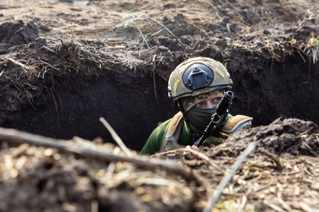 DONETSK Reg., UKRAINE - Feb. 14, 2024: A Ukrainian Armed Forces soldier is seen with a rifle in a trench at a combat position during a combat mission in Donetsk region, Ukraineのeditorial素材