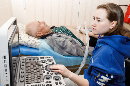 DONETSK Reg, UKRAINE - Apr. 21, 2024: A young woman ultrasound doctor from Frida Volunteer Mission is seen performing an abdominal ultrasound on an elderly manのeditorial素材